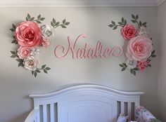 a baby's room decorated with pink flowers and name decals on the wall