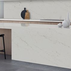 a white marble kitchen island with stools and vases on the counter top in front of it