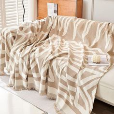 a zebra print blanket sitting on top of a white couch next to a wooden headboard