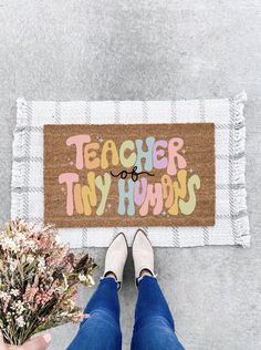 a person standing in front of a door mat with the words teacher thyn on it