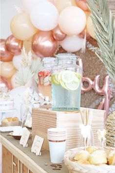 a table topped with drinks and food next to balloons