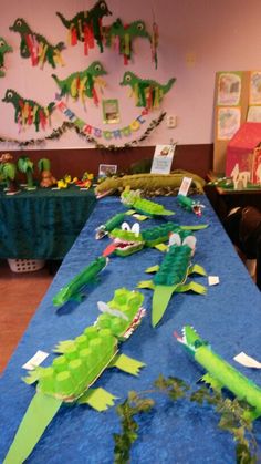 some paper alligators are laying on a blue table cloth in the middle of a room