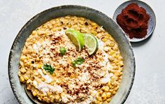 a bowl filled with mexican food and garnished with cilantro, sour cream and lime