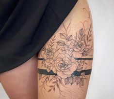 a woman's thigh with flowers on it and black ribbon around the leg,