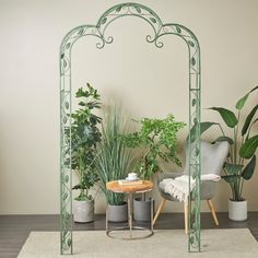 a room filled with lots of potted plants next to a table and two chairs