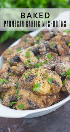 baked parmesan garlic mushrooms in a white dish on a wooden table with herbs