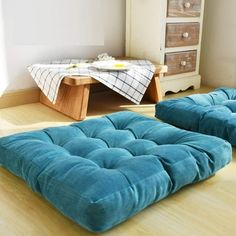 two blue futons sitting on top of a wooden floor next to a dresser