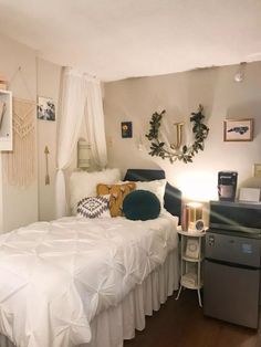 a bed with white sheets and pillows next to a small desk in front of a window