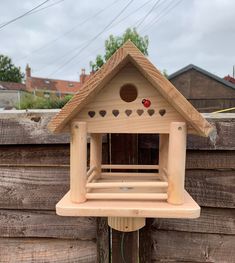 a wooden bird house with hearts on the roof