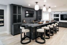 a kitchen with an island and bar stools in the center, surrounded by black cabinets