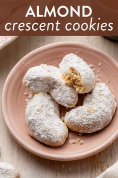 almond crescent cookies on a pink plate with powdered sugar and crumbled edges