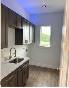 an empty kitchen with wood floors and gray cabinets is seen in this image from the doorway