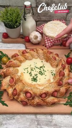 this is an image of a cheesy dish on a cutting board with vegetables and bread