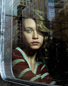 a young woman looking out the window of a train with skyscrapers in the background