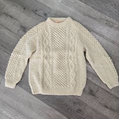 a white sweater sitting on top of a wooden floor