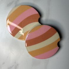 two pink and orange striped buttons on a white surface