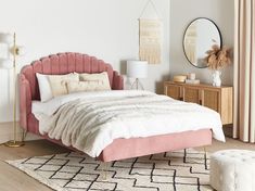 a bed with pink velvet headboard and foot board in a white room next to a mirror