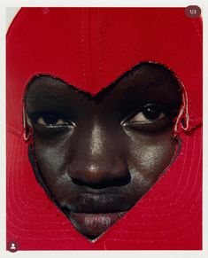 a woman's face is seen through a hole in a baseball cap that has been cut into the shape of a heart