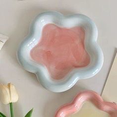 two pink and white plates sitting on top of a table next to tulips