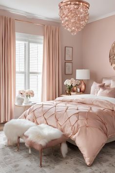 a bedroom decorated in pink and gold with a chandelier hanging from the ceiling