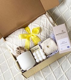 an open box with candles, soaps and other items in it on a bed