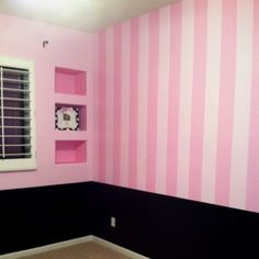 a room with pink and black striped walls, white shutters, and a window