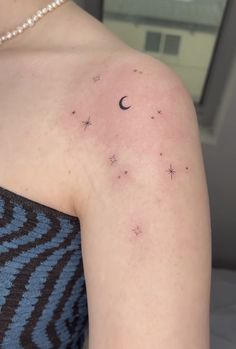 a woman's upper arm with stars and a crescent tattoo on her left shoulder