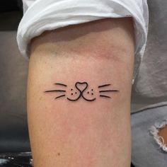 a cat's face with a heart tattoo on the left side of the leg