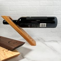 a bottle of wine is sitting on top of a wooden block with a knife sticking out of it