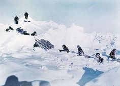 a group of people climbing up the side of a snow covered mountain