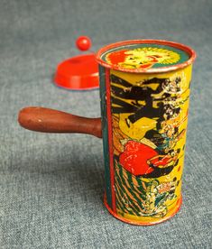 an old fashioned toy with a wooden handle and red button on the top, sitting on a blue surface