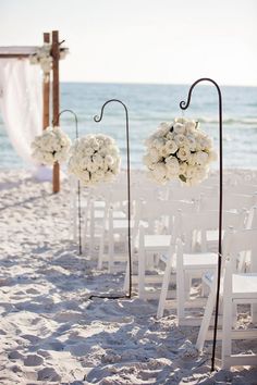 an image of a beach wedding with white flowers on the aisle and chairs in the sand