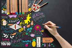 a person is drawing on a blackboard with colored pencils and crayons