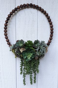 a wooden beaded necklace with succulents and wood beads hanging from it