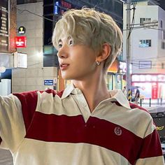 a young man holding a nintendo wii game controller in his right hand while standing on the street