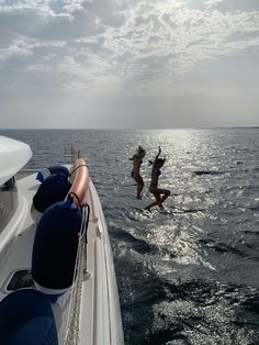 two people jumping into the water from a boat