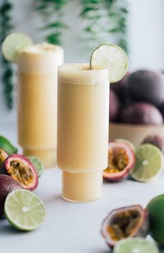 two glasses filled with liquid sitting on top of a table next to sliced kiwis