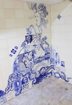 a blue and white tiled bathroom with an artistic mural on the wall above it's toilet