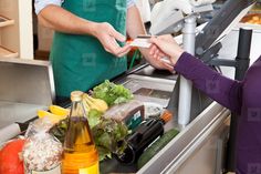 two people standing in front of a counter with food on it and one person holding a knife