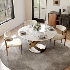 a dining room table with white chairs and a round rug in front of the window