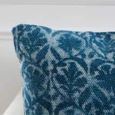 a blue and white pillow sitting on top of a couch next to a window sill