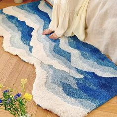 a child is sitting on the floor in front of a blue and white area rug