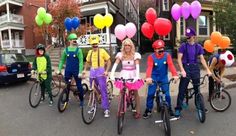 a group of people on bikes with balloons in the shape of heart shaped shapes and clowns