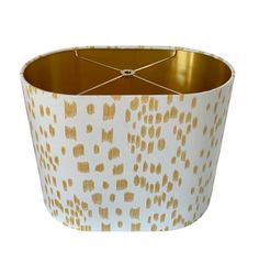 a white and gold lamp shade with dots on it