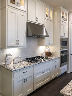 a kitchen with white cabinets and marble counter tops, stainless steel appliances and an oven