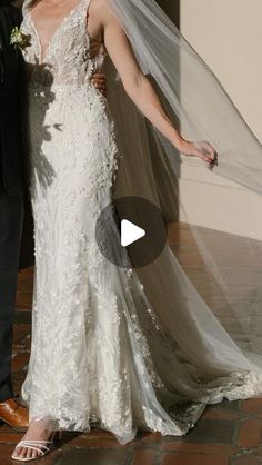 a man and woman standing next to each other in front of a wall wearing wedding dresses