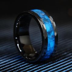 a ring with blue and black inlays on the inside is sitting on a table