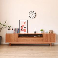 a wooden entertainment center with a clock on the wall above it and plants in pots