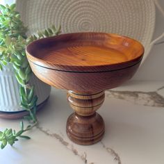 a wooden bowl sitting on top of a table next to a potted succulent