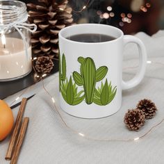 a cup of coffee sitting on top of a table next to pine cones and candles